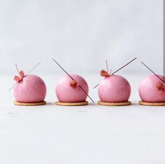 four donuts with pink icing are arranged in a row on top of each other