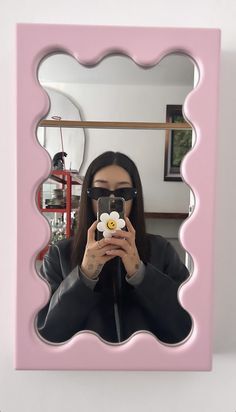 a woman taking a selfie in front of a mirror with a flower on it