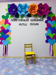 a wooden chair sitting in front of a wall with paper flowers and words on it