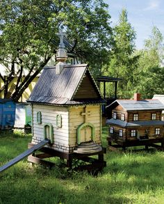 several small wooden houses sitting on top of grass in the middle of a park with lots of trees