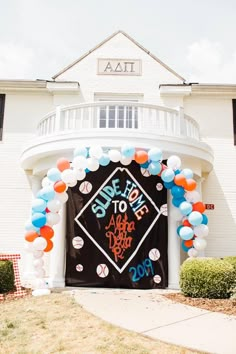 an entrance to a baseball themed party with balloons and decorations on the front door is decorated in black, orange, and white colors