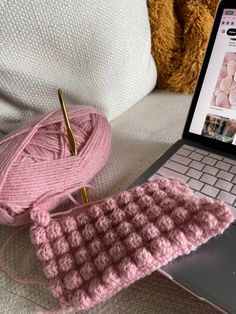 a laptop computer sitting on top of a bed next to a pink crocheted mouse