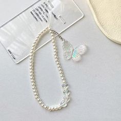 a white necklace with a butterfly on it and a tag attached to the bead