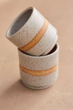 three ceramic cups stacked on top of each other with speckles and gold bands