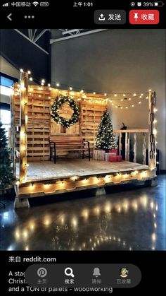 a stage set up with christmas lights and wreath on the top, surrounded by small trees