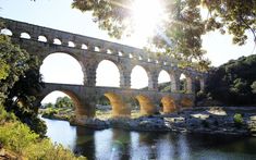 an old stone bridge spanning the width of a body of water with arches over it