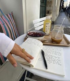 a person sitting at a table with an open book and writing utensils on it