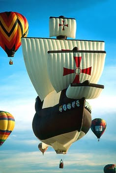 several hot air balloons flying in the sky with one boat on it's back