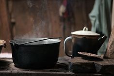 an old fashioned cast iron skillet and pot on a stove top with steam rising from it