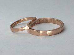 two gold wedding rings sitting on top of each other