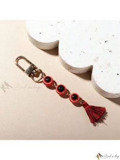 a keychain with two red eyes and a tassel hanging from it's side