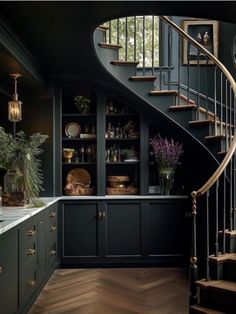 an elegant kitchen with dark green cabinets and wood floors, along with a spiral staircase