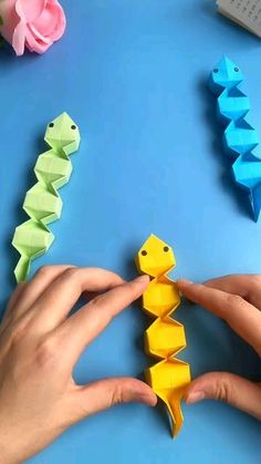 someone is making origami fish out of paper on a blue table with other items