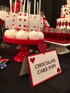 a table topped with lots of cake pops covered in white frosting and red hearts