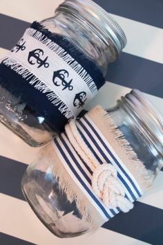 two mason jars sitting on top of a striped tablecloth covered floor next to each other