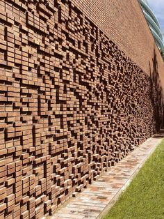 a large brick wall next to a grassy field