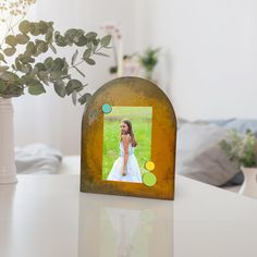 a photo frame sitting on top of a table next to a vase with flowers in it