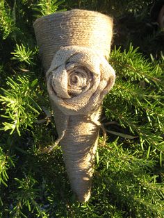 a rolled up towel sitting on top of a green bush covered in leaves and grass