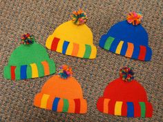 four knitted hats with pom poms on them sitting on the floor next to each other