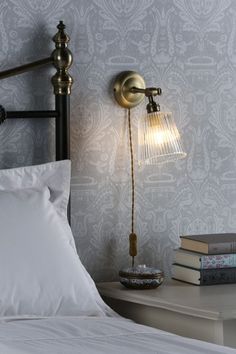 a lamp that is on top of a bed next to pillows and books in a room