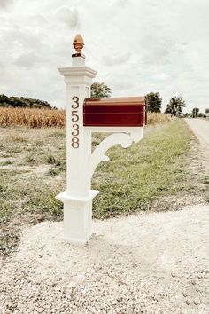 a white mailbox sitting on the side of a road next to a grass covered field