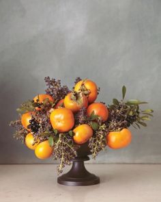 a vase filled with lots of oranges on top of a table