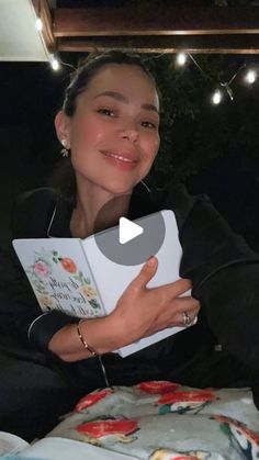 a woman sitting on top of a bed holding a book