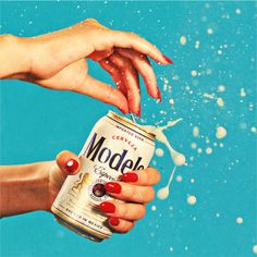 a woman holding a can of soda in her hand with bubbles coming out of it