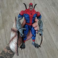 a hand holding a toy that looks like a spider - man with horns and claws