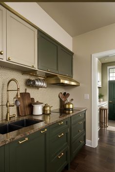 a kitchen with green cabinets and gold accents on the counter tops, along with an open door leading to another room