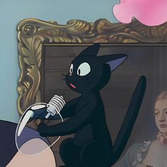 a black cat sitting on top of a table next to a woman holding a microphone