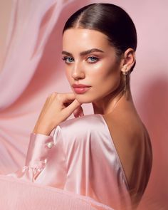 a woman in a pink dress posing for the camera with her hand on her chin