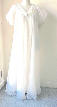 Absolutely gorgeous vintage early 60s Jenelle of California peignoir double chiffon gown and robe set in white/ivory, floor length. The gown is sleeveless with v-neckline front and back accenting the neckline there is a trim of ivory satin finished with a chiffon flower in the center front. The robe has short puff double chiffon sleeves  that have elastic 1" from the hem creating a ruffle. There is a snap closure under the chiffon flower. Gown has matching neckline to the robe. The body of both robe and gown is double chiffon with a ruffle at the hem of gown and robe, they are full and flowing and elegant when worn.  Jenelle of California was a premier manufacturer of these peignoir sets in the 50s and 60s and they really are fabulous. The flow and elegant feel when worn create a special e Vintage Peignoir Sets, Retro Pjs, Vtuber Inspiration, Chiffon Sleeves, Peignoir Sets, Chiffon Flower, Vintage Nightgown, Chiffon Flowers, Chiffon Gown