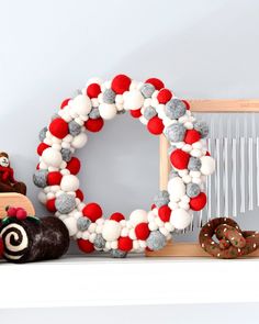 a decorated christmas wreath sitting on top of a mantle next to cookies and pretzels