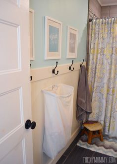 a bathroom with two pictures hanging on the wall and a towel rack in the corner