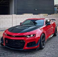 a red chevrolet camaro parked in front of a building