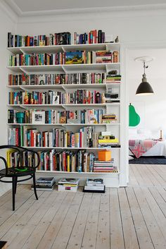 a bookshelf filled with lots of books next to a black chair and table