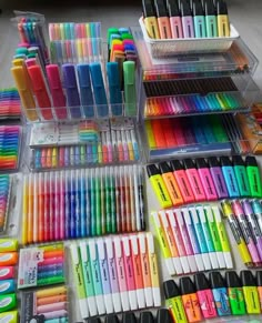 many different colored pens and markers in plastic containers on a table next to each other