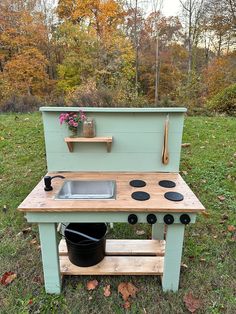 an outdoor play kitchen made out of wood with pots and pans on the stove