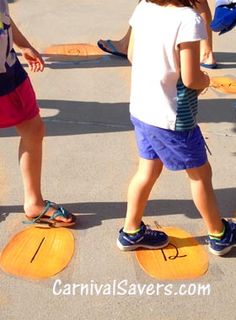 two children are standing on skateboards in the middle of an asphalt area with other kids