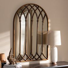 a mirror sitting on top of a dresser next to a table with a lamp and vase