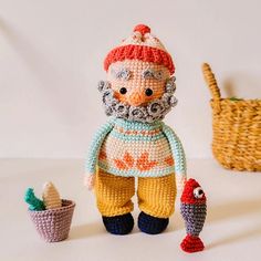 there is a crocheted doll next to two small baskets and a toy bird