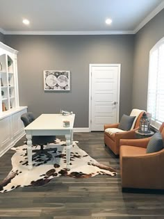 a living room filled with furniture and a cow hide rug