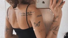 a woman taking a selfie with her cell phone in front of her face and tattoos on her back