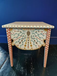 an ornate painted table against a blue wall