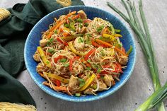 a blue bowl filled with noodles and vegetables