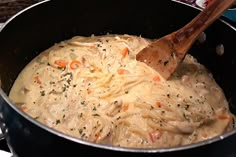 a wooden spoon in a pot filled with pasta