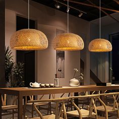 three lights hanging from the ceiling above a table with chairs and vases on it