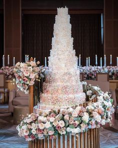 a tall wedding cake sitting on top of a table next to flowers and candles in the background