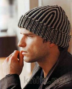 a man wearing a knitted hat looks out the window while holding his hand to his ear